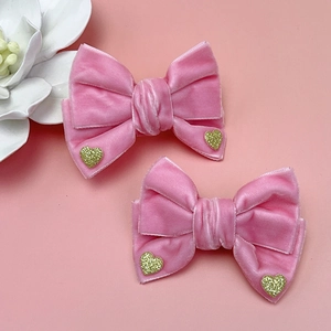 Detalle de dos lazos para el pelo en terciopelo rosa con corazones dorados brillantes