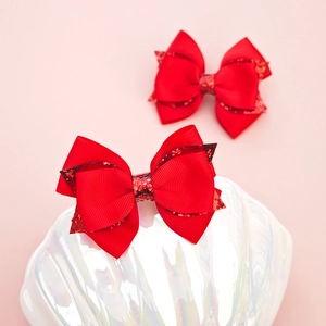 Détail de barrettes à nœuds rouges scintillants avec ruban gros-grain à double couche