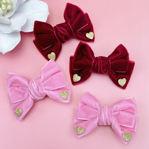 Primer plano de cuatro lazos de pelo de terciopelo con corazones dorados en rojo y rosa