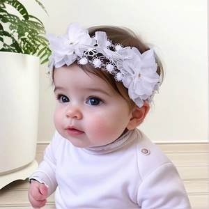 Vue détaillée d'un bandeau en dentelle blanche pour bébé avec fleur de soie et perles