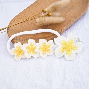 Close-up of handmade white crochet flower hair clip and soft nylon headband for baby