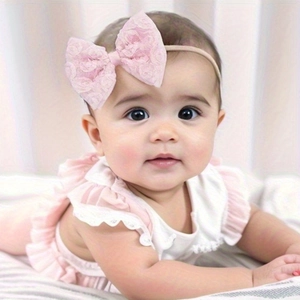 Close-up of baby girl wearing a soft pink lace bow headband with delicate rose patterns