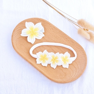 Detailed macro view of ivory knitted flower hair clip and soft nylon headband set