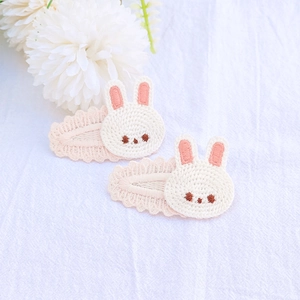 Gros plan de deux pinces à cheveux lapin de Pâques tricotées avec broderie rose délicate
