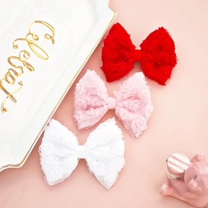 Detail of baby lace bow hair clips in red, pink, and white on a decorative tray
