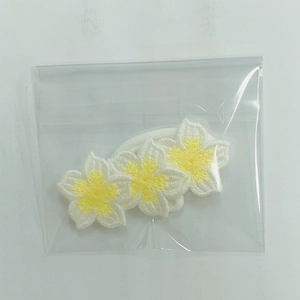 Macro detail of three handmade embroidered white flowers on a soft nylon hairband