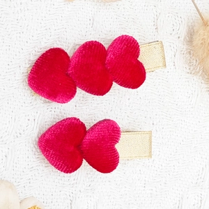 Nahaufnahme der Herz-Haarspangen mit rosa Samtstruktur und goldenem Schleifenband