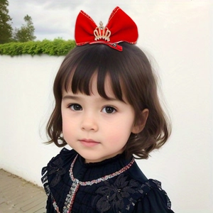 Détail d'un nœud papillon en velours rouge avec couronne dorée et strass sur une fille