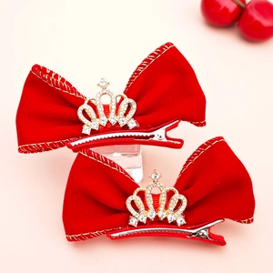 Gros plan sur pince à cheveux nœud en velours rouge avec couronne de strass et bord doré