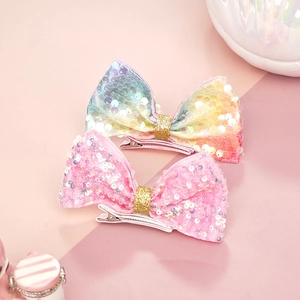 Dettaglio di fiocchi per capelli con paillettes arcobaleno e nastro glitterato in metallo
