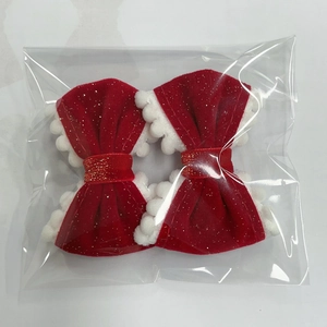 Detail of red velvet hair bows with white fur edges and gold glitter in plastic packaging