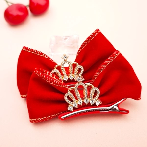 Détail de la pince à cheveux en velours rouge avec couronne dorée et décor de strass