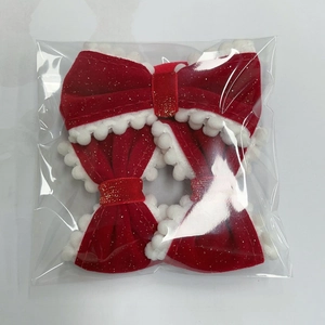 Three-piece set of red velvet bow hair clips with white pom pom trim in clear packaging