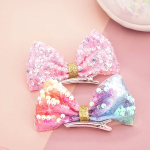 Dettaglio dei fermagli a fiocco con paillettes rosa e iridescenti con clip a becco d'anatra