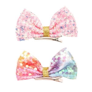 Dettaglio di fermagli per capelli con fiocchi di paillettes rosa e arcobaleno e glitter