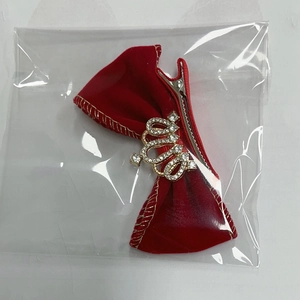 Détail d'une pince à cheveux nœud en velours rouge avec couronne dorée et strass