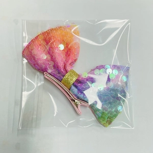 Dettaglio del fiocco con paillettes arcobaleno per bambini e clip a becco d'anatra in metallo