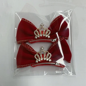 Vue détaillée des barrettes nœuds en velours rouge avec bordure dorée et couronnes strass