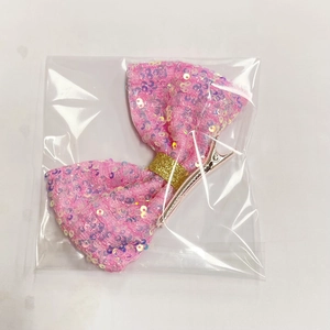 Dettaglio del fermaglio a fiocco rosa con paillettes in confezione trasparente