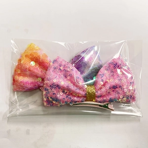 Dettaglio di fermagli per capelli a fiocco glitterati in rosa e viola in confezione trasparente