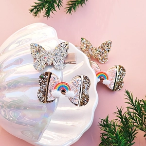 Close-up of sparkling sequin butterfly hair clips and rainbow bows in a shell tray