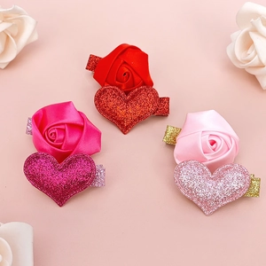 Detail view of handmade satin rose and glitter heart hair clips in three shades of red