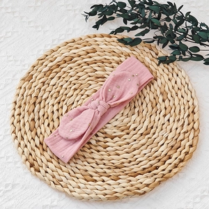 Detailed macro view of pink fabric baby headband featuring gold foil polka dots and bow