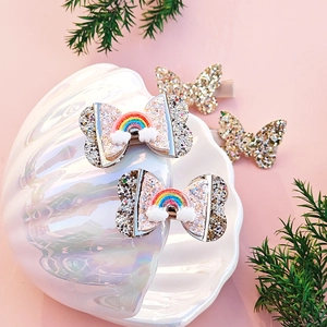 Detailed view of rainbow bow hair clips and glitter butterfly clips in a shell tray