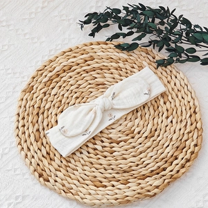 Detail of cream floral baby headband with rabbit ear bow on a rustic natural background
