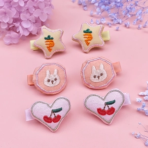 Close-up of 6-piece embroidered fabric hair clips with star, rabbit and cherry motifs