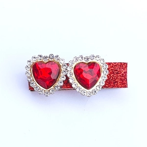 Close-up of girls heart hair clips with red faceted gemstones and sparkly glitter finish