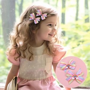 Rainbow bow hair clips for girls with cloud accents shown in a scenic outdoor setting