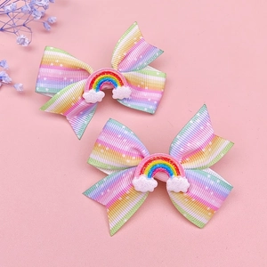 Detail of two rainbow grosgrain ribbon bow hair clips with cloud and glitter decorations