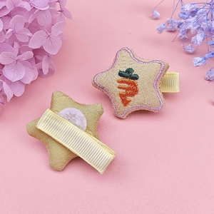 Close-up of star-shaped fabric hair clips with carrot embroidery and fabric-wrapped duckbill clips