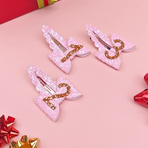 Detailed view of pink glitter birthday hair clips with golden numbers one two and three