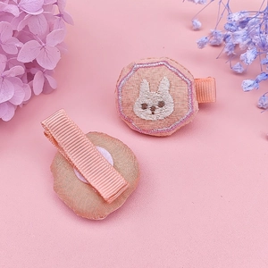 Detail view of pink fabric hair clip with a cute white bunny embroidery for baby girls