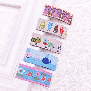 Close-up of five cartoon fabric hair clips with detailed floral and animal embroidery patterns