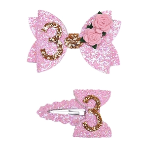 Detail of pink glitter bow hair clip with gold number 3 and 3D rose for 3rd birthday