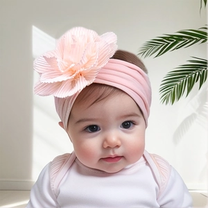 Detail of baby headband with a large pink pleated fabric flower on a soft nylon band