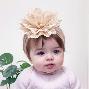 Detail of baby headband with a large layered cream flower on soft pink elastic fabric