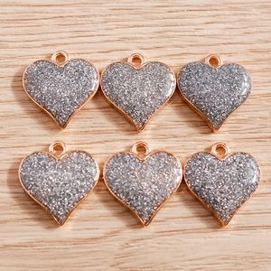Lot de 6 pendentifs cœur avec paillettes argentées et cadre en or rose sur fond bois