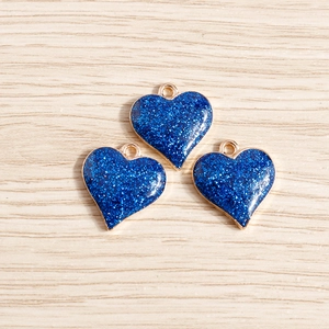 Vue macro de breloques cœur pailletées bleues avec bords dorés sur bois clair