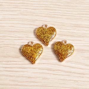 Détail de breloques en forme de cœur à paillettes dorées sur bois pour bijoux DIY
