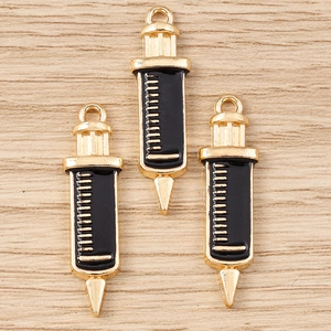 Détail macro de pendentifs en forme de seringue en alliage et émail noir pour bijoux