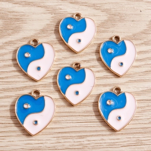 Detail of six blue and white heart-shaped Yin Yang enamel charms on a light wood background