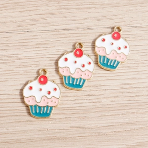 Detalle de tres dijes de cupcake de esmalte con anillas sobre un fondo de madera