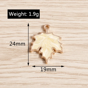 Detail of maple leaf charm in cream enamel with golden alloy edge and size 24mm by 19mm