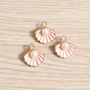 Tres elegantes colgantes de concha con esmalte rosa y perla blanca sobre madera