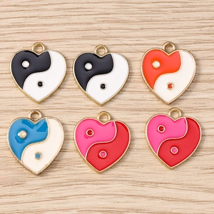 Detail of colorful enamel heart Yin Yang charms with alloy edging on wooden texture