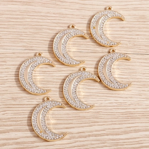 Detail shot of six gold alloy crescent moon pendants paved with sparkling white rhinestones